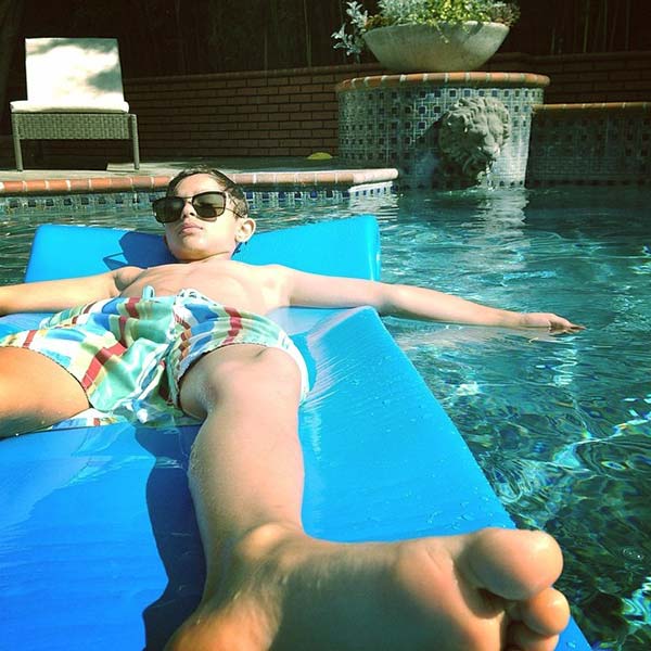 Image of Justin Chambers son Jackson basking in the sun as he floats in a pool